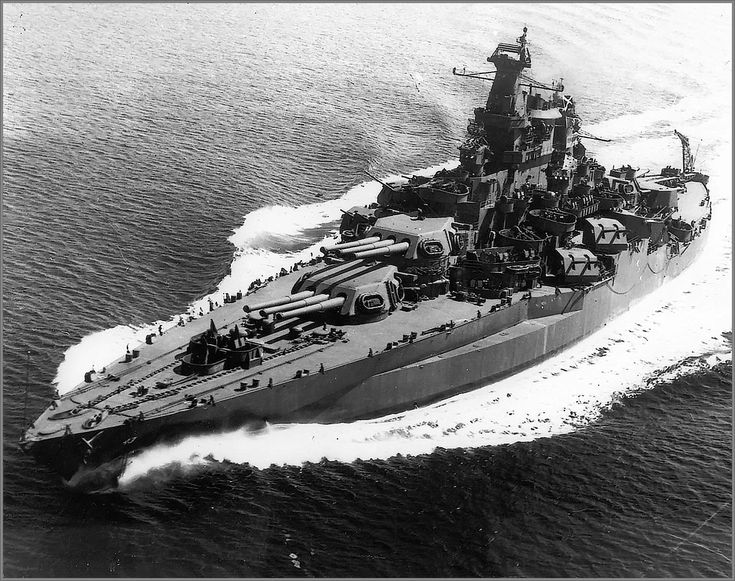 an aerial view of a battleship in the water with people on it's deck