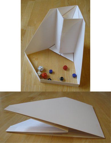 an origami box is open and sitting on the floor next to other pieces of paper