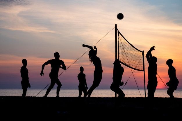 silhouettes of people playing volleyball on the beach at sunset