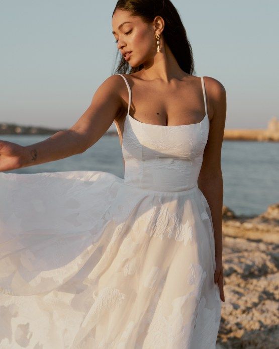 a woman in a white dress standing on the beach