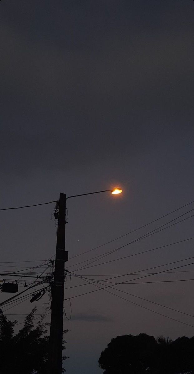 the sun is setting behind power lines and telephone poles on a dark night with no clouds