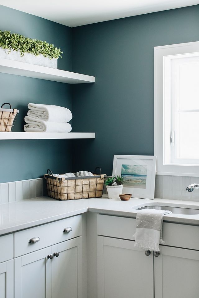 a kitchen with blue walls and white cabinets is pictured in this image, there are towels on the shelves above the sink