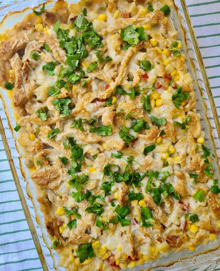 a casserole dish with chicken, corn and cilantro in it on a striped cloth