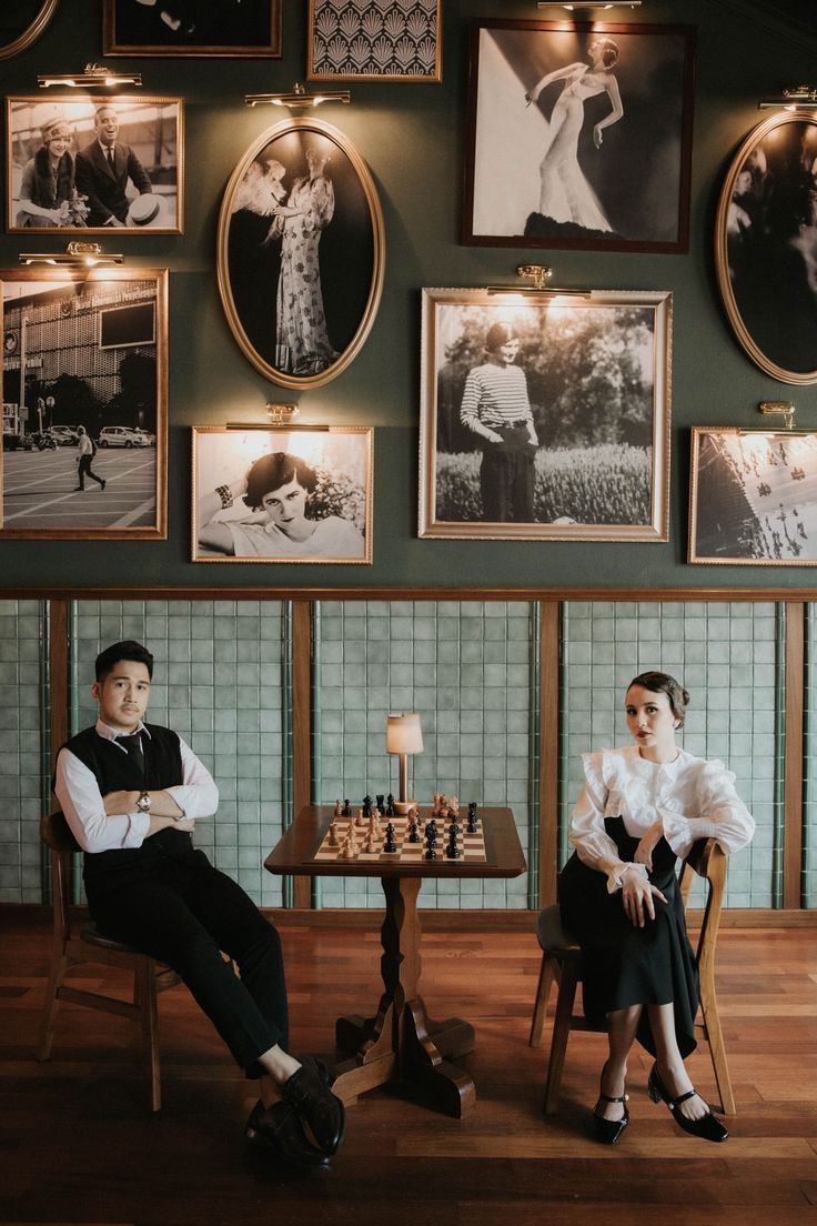 two people sitting at a table in front of pictures on the wall