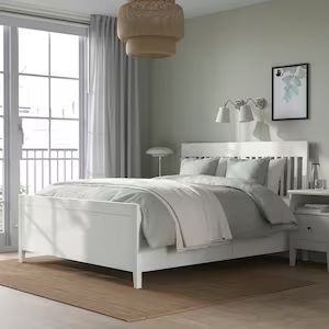 a white bed sitting in a bedroom next to a window