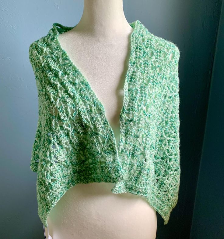 a white mannequin wearing a green knitted shawl over it's shoulder