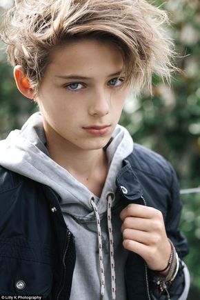 a young boy with blue eyes wearing a jacket