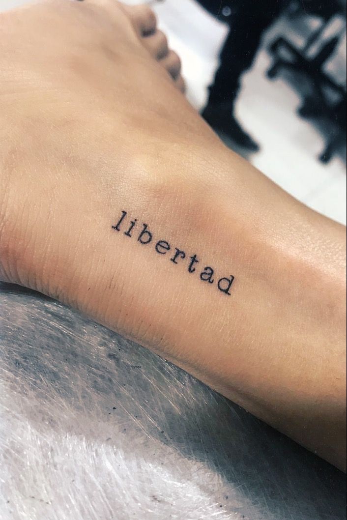 a woman's foot with the word libertad tattooed on her left leg