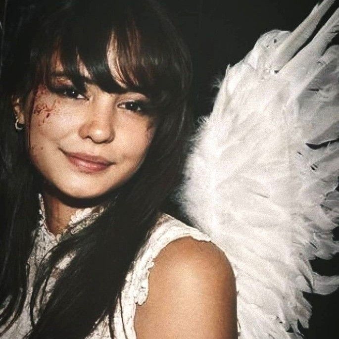 a young woman with white wings on her head and chest, posing for the camera