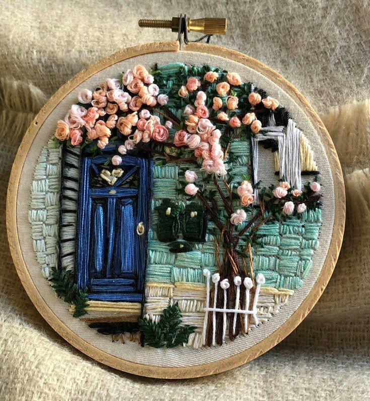 a blue door surrounded by pink flowers and greenery on a beige fabric background with a wooden frame