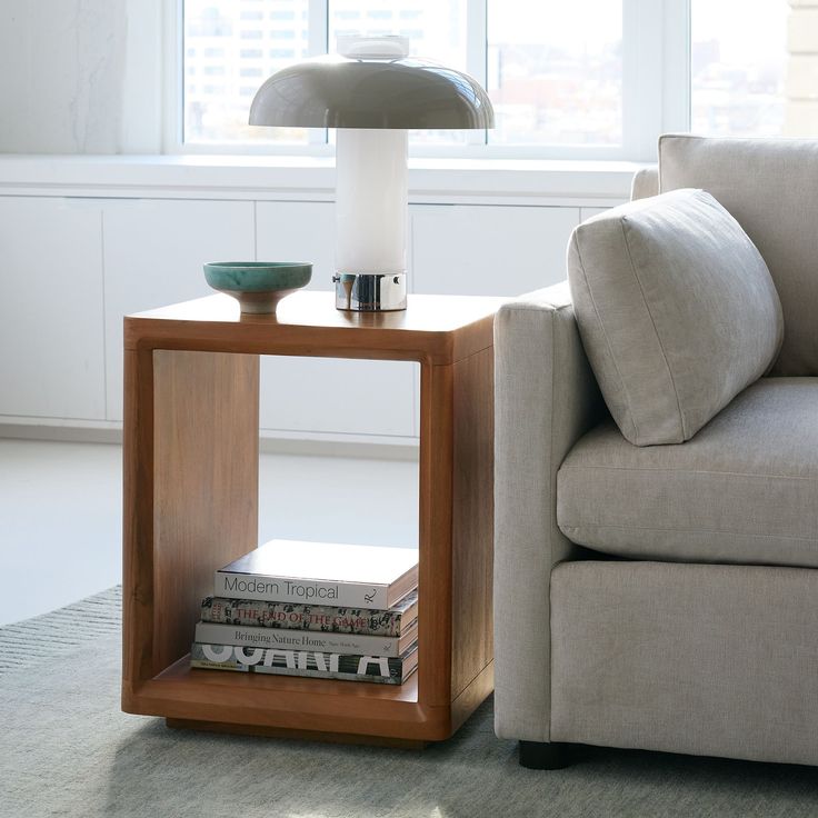 a table that has some books on it next to a couch with a chair in the background