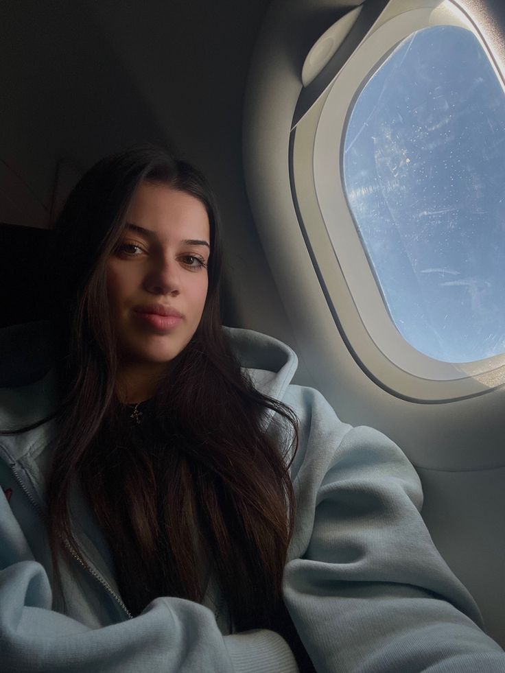 a woman sitting in an airplane looking out the window