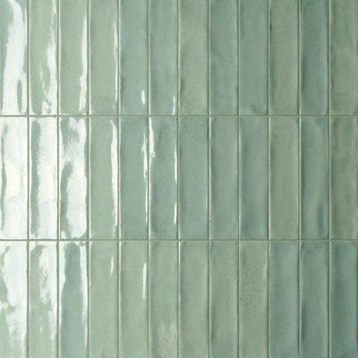 a white toilet sitting next to a green tiled wall