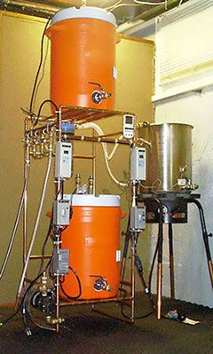 a large orange barrel sitting in the middle of a room next to a machine and some wires