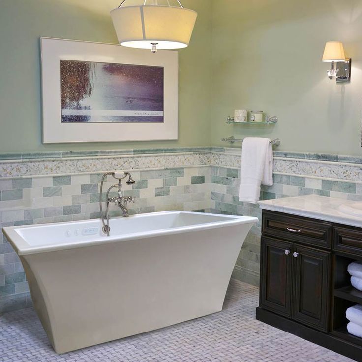 a white bath tub sitting in a bathroom next to a sink and vanity with towels on it