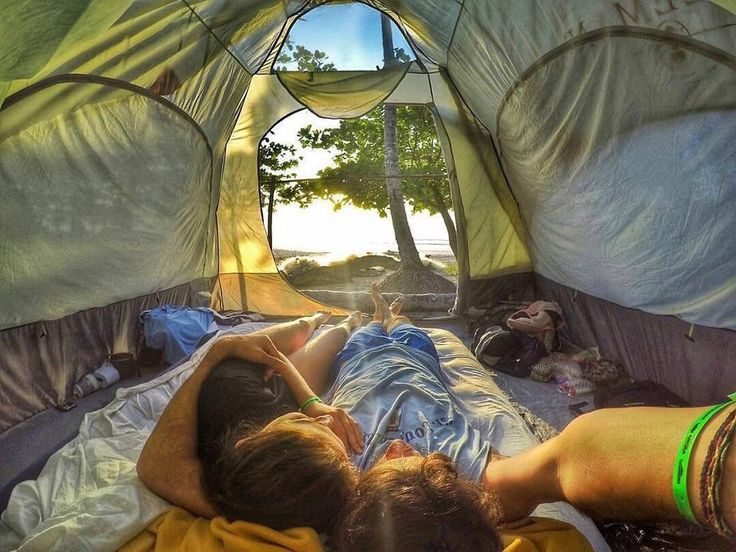 two people laying in a tent with the sun shining on them and trees behind them