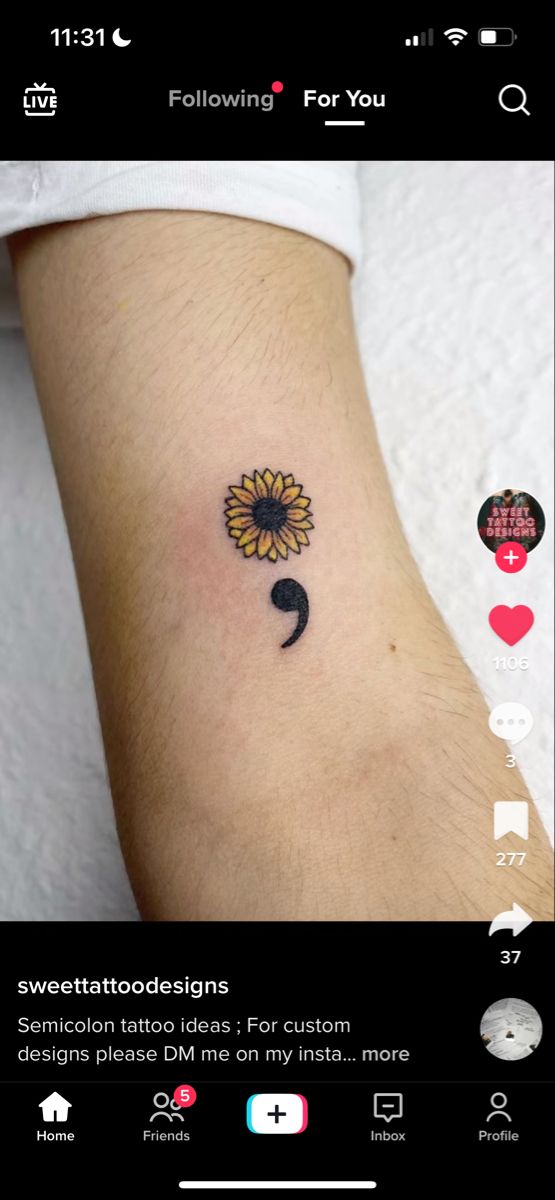 a small sunflower tattoo on the left side of the arm, with other tattoos below it