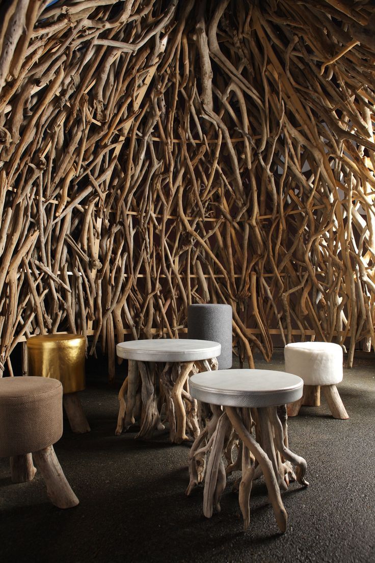 two white stools sitting next to each other in front of a wall made out of branches