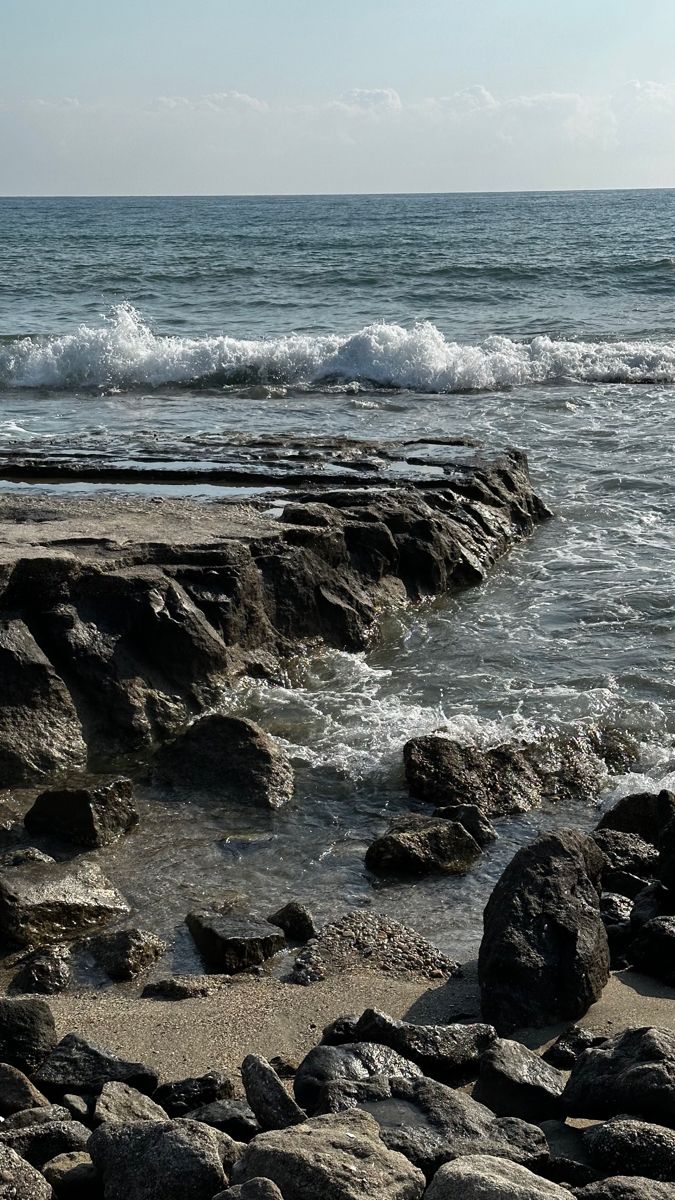 an ocean view with rocks and waves coming in