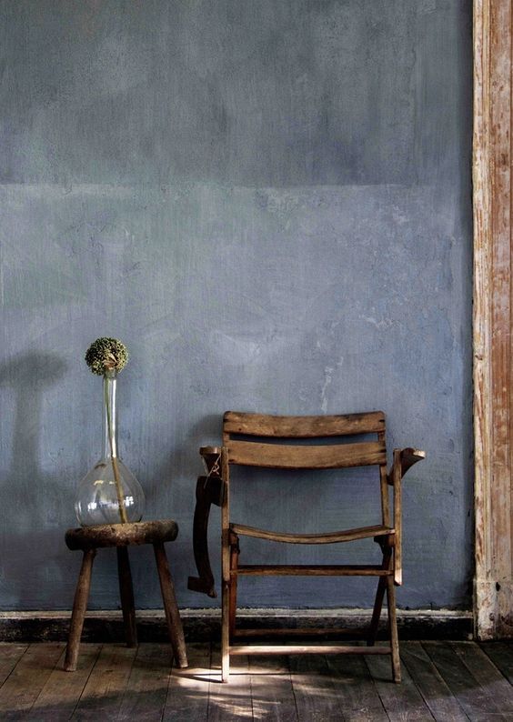 a chair and vase sitting next to each other in front of a wall with blue paint