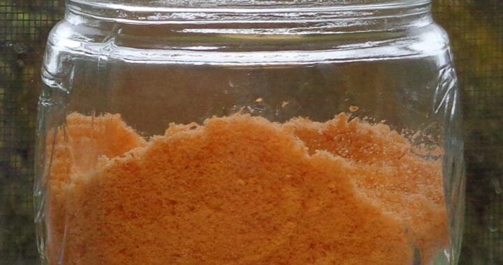 a glass jar filled with orange colored powder