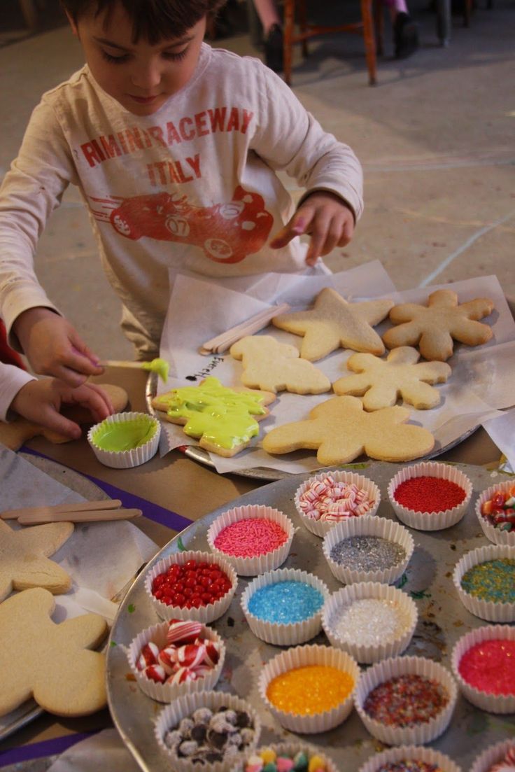 two children making cookies on a table with paper plates and bowls filled with candy canes