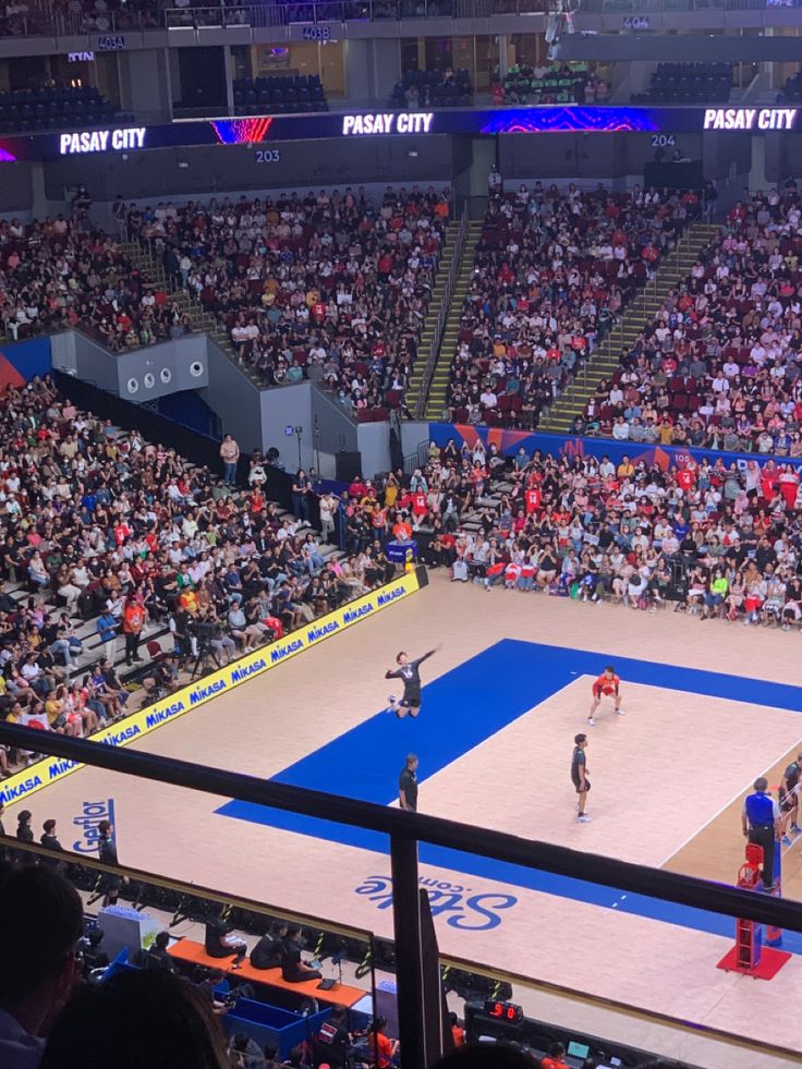 an indoor basketball court with people watching it