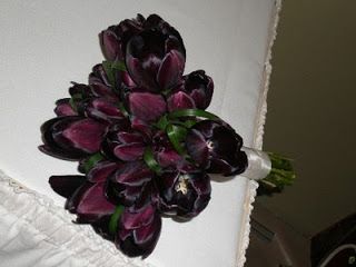 a bouquet of flowers sitting on top of a white cloth covered bed frame next to a mirror