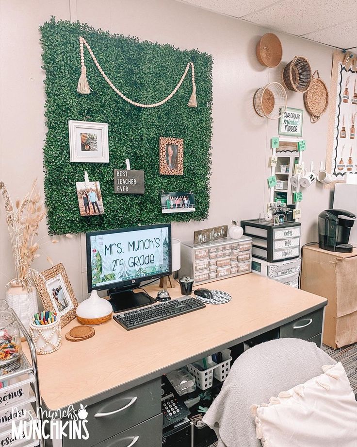 a desk with a computer on top of it in front of a large green wall