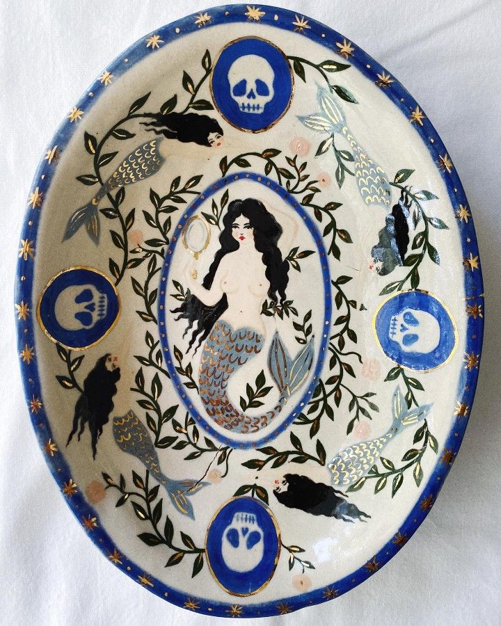 a blue and white plate with an image of a mermaid on the side, surrounded by other sea creatures