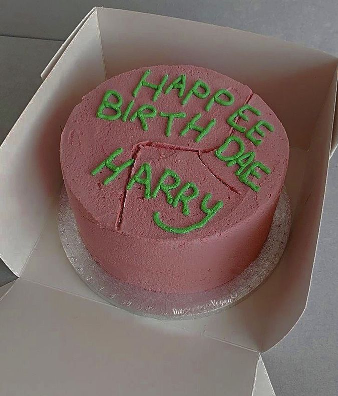 a pink birthday cake with green frosting in a box