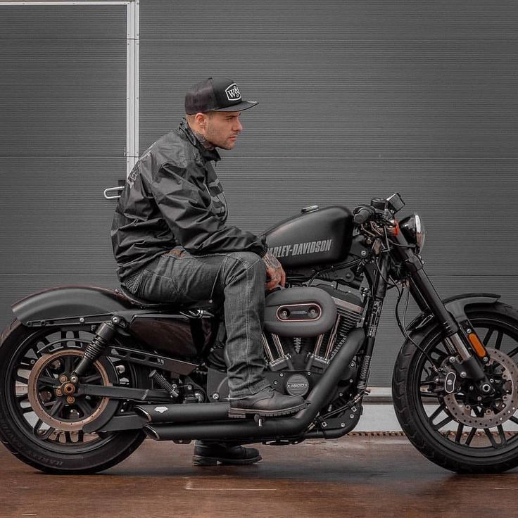 a man riding on the back of a motorcycle in front of a gray building with a garage door