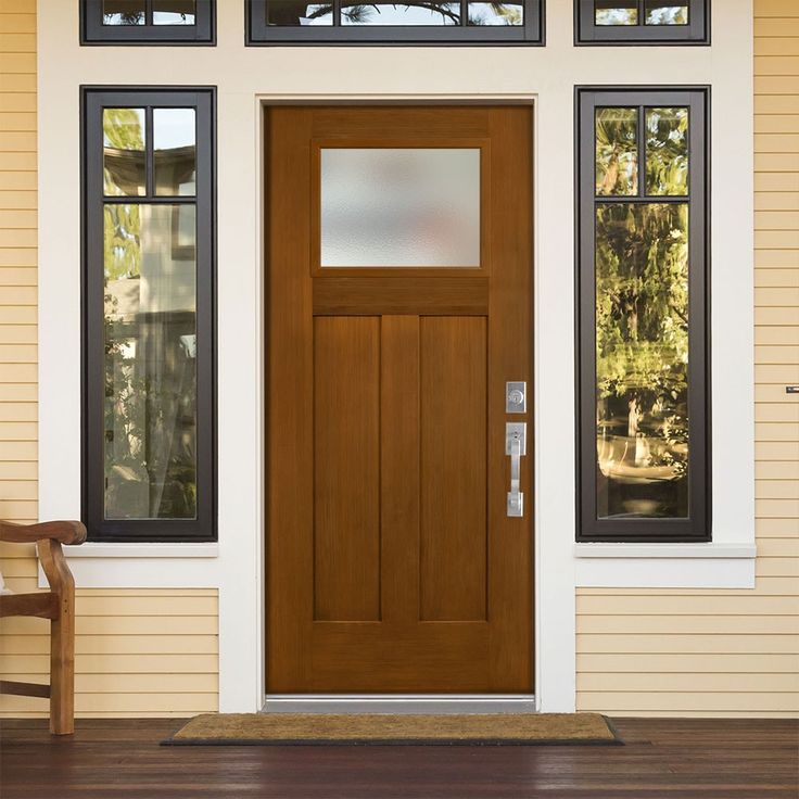 a wooden door on the side of a white house with two windows and a chair