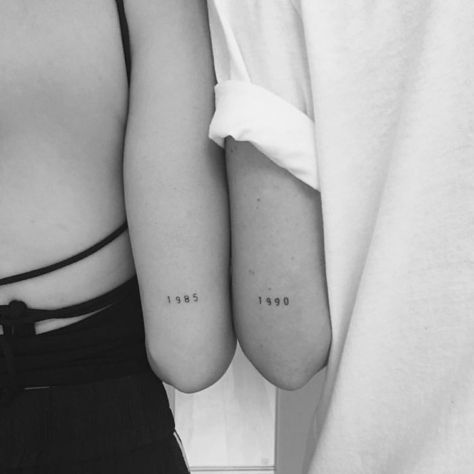 two people with matching tattoos on their arms, one is holding the other's arm