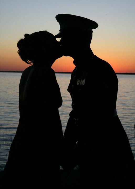 the silhouette of two people kissing in front of a body of water at sunset or dawn