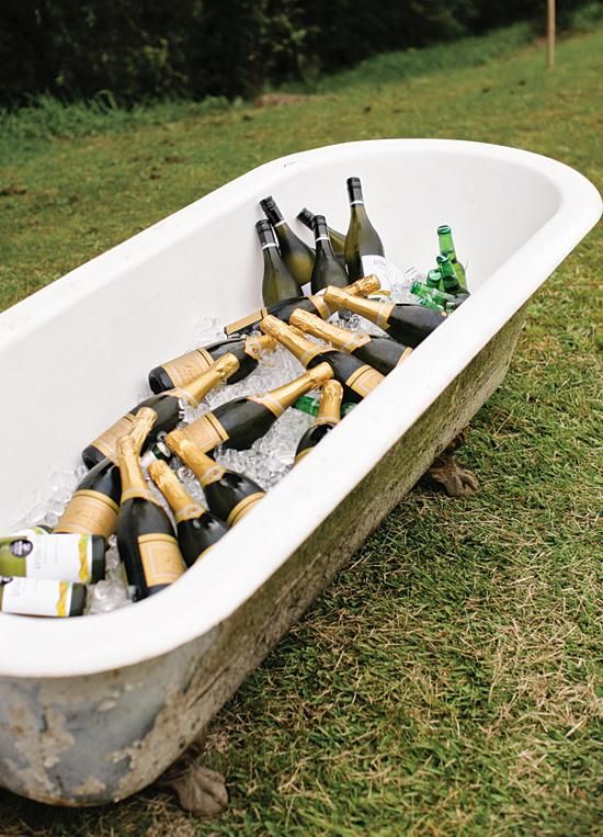 a tub filled with bottles of beer sitting in the grass