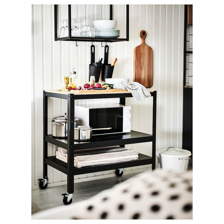 a kitchen cart with various items on it in front of a white wall and floor