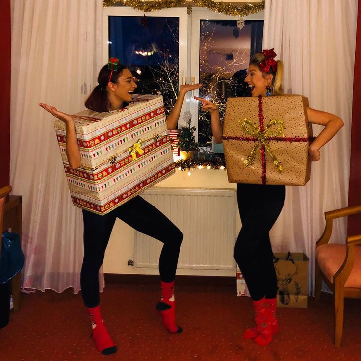 two women are holding presents in front of a window with christmas decorations on them and one is wearing red boots