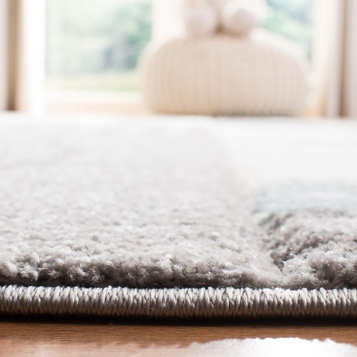 a close up view of a rug on the floor in front of a bed with a teddy bear