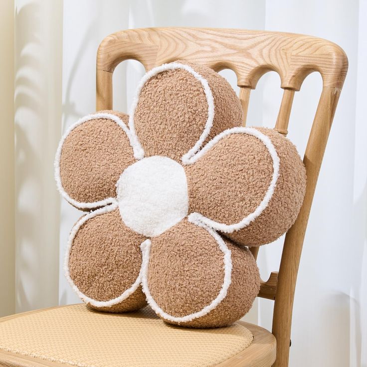 a stuffed flower sits on top of a wooden chair