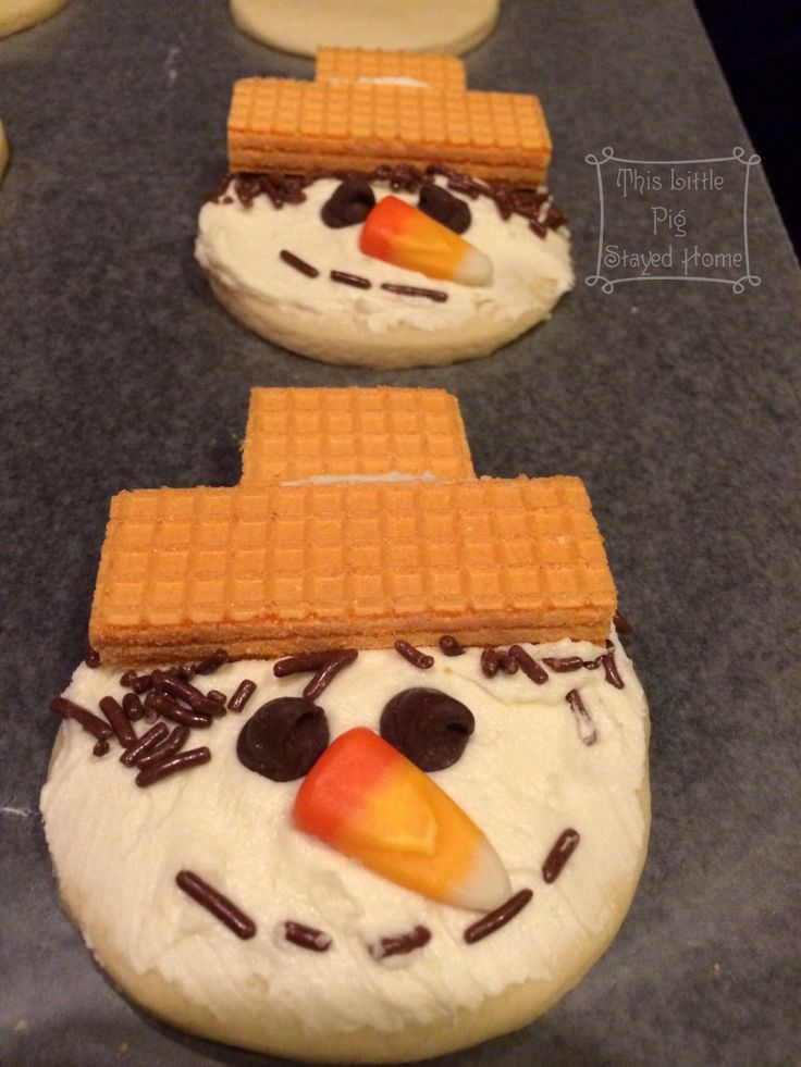 two snowmen made out of waffles on top of a cookie sheet covered in frosting