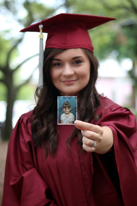 a woman in graduation gown holding up a photo