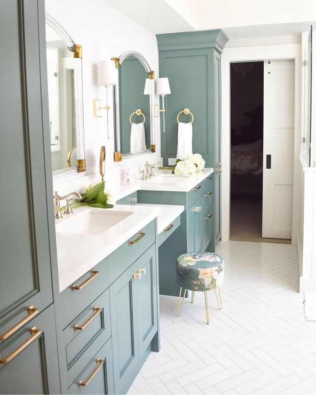 a bathroom with blue cabinets and gold handles on the sink, along with a white tiled floor