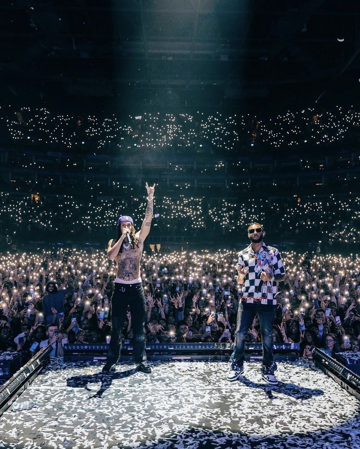 two men standing on top of a stage with their hands in the air