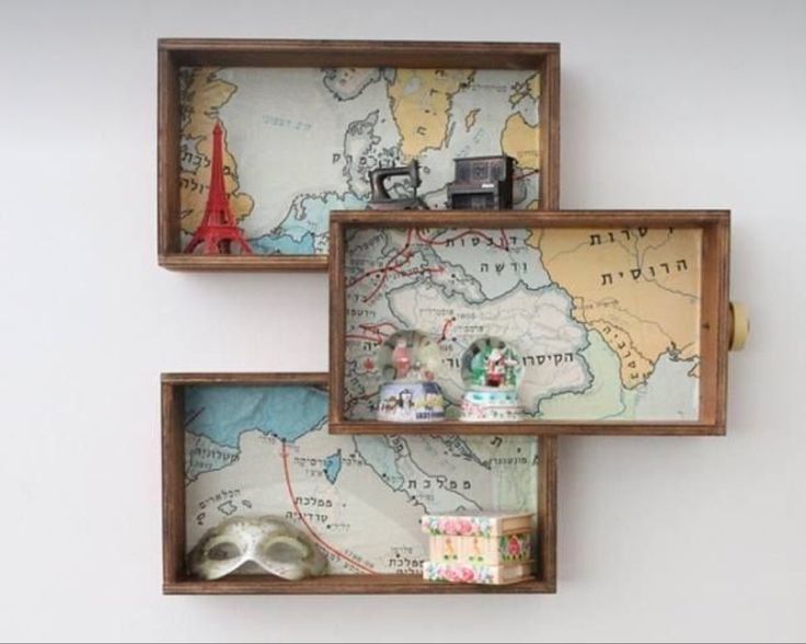 three wooden boxes with maps and other items in them on the wall, one is empty