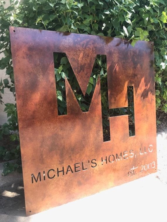 a large metal sign that says michael's homes, inc in front of some bushes