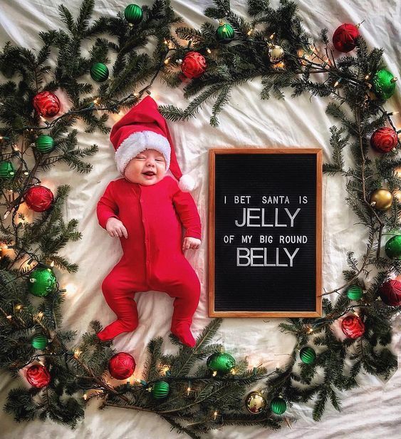 a baby wearing a santa hat laying next to a chalkboard that says, i get santa is jelly of my big round belly