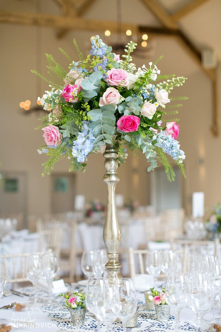 a tall silver vase filled with pink and blue flowers on top of a white table