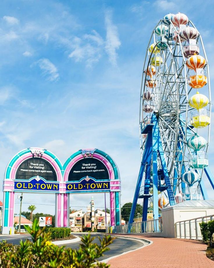 an amusement park with a ferris wheel and colorful archways for the entrance to it