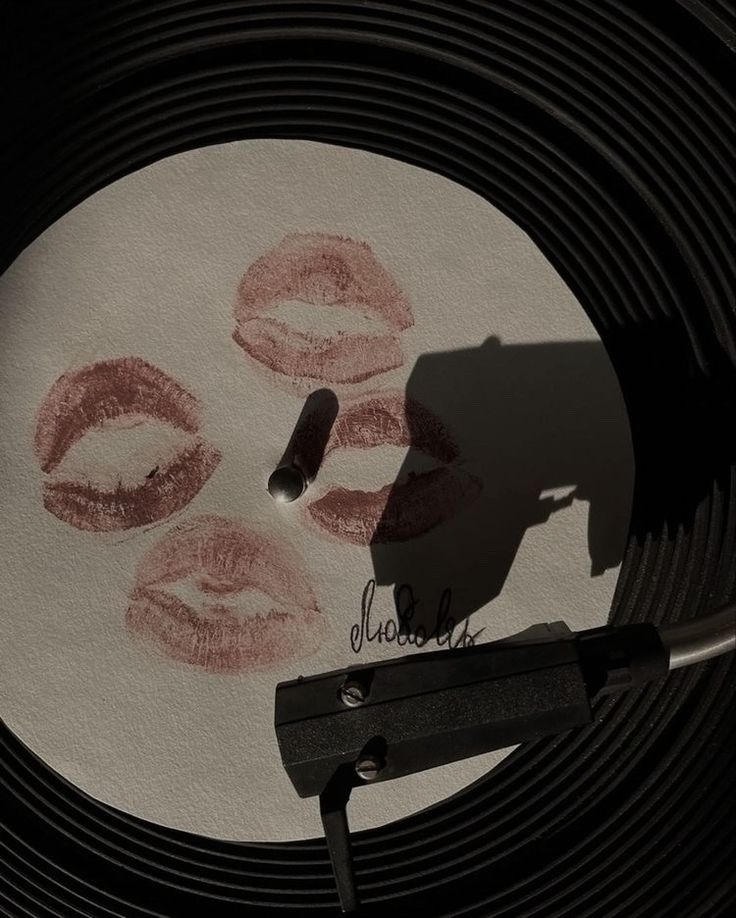 a record with lipstick drawn on it next to a pair of scissors